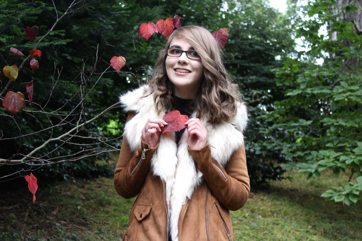 Photo of Elin holding a red heart shaped leaf