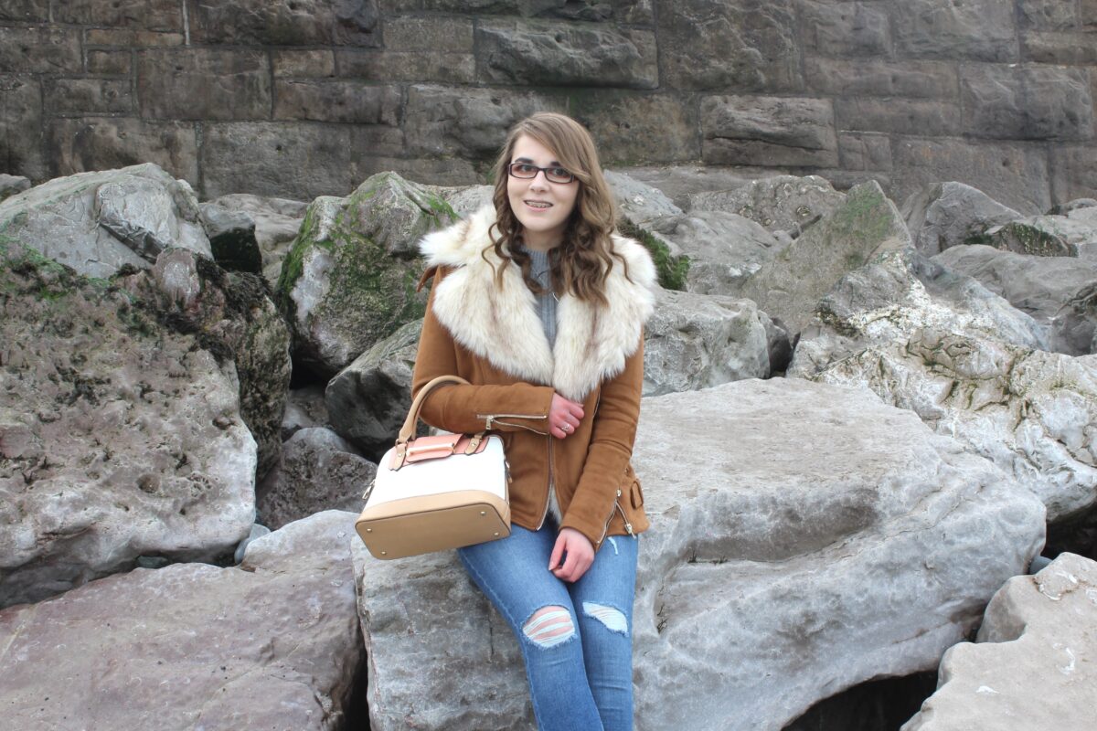 A photo of Elin sitting on rocks on the beach