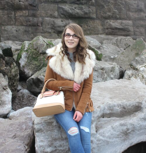 A photo of Elin sitting on rocks on the beach