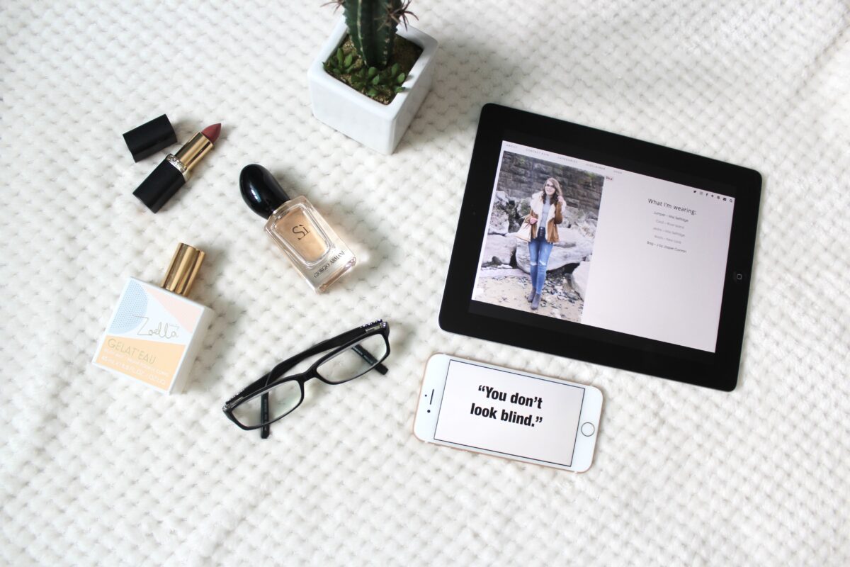 A photo of a phrase on my phone which says 'you don't look blind,; there is a pair of black glasses beside it and a couple of perfumes
