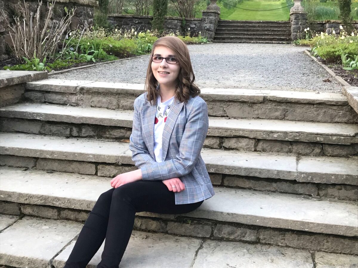 A photo of Elin in grey check blazer sitting on steps
