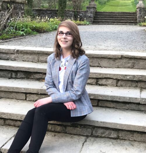 A photo of Elin in grey check blazer sitting on steps