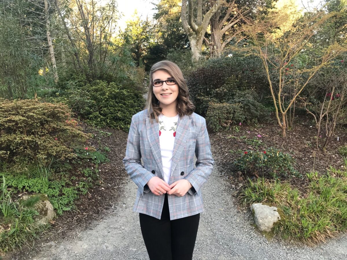 A photo of Elin wearing a check grey blazer, white t-shirt and black skinny jeans