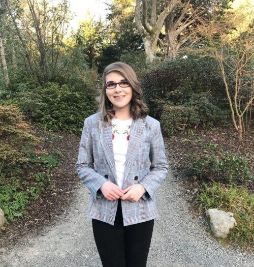A photo of Elin wearing a check grey blazer, white t-shirt and black skinny jeans