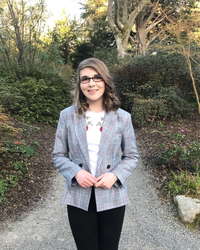 A photo of Elin wearing a check grey blazer, white t-shirt and black skinny jeans
