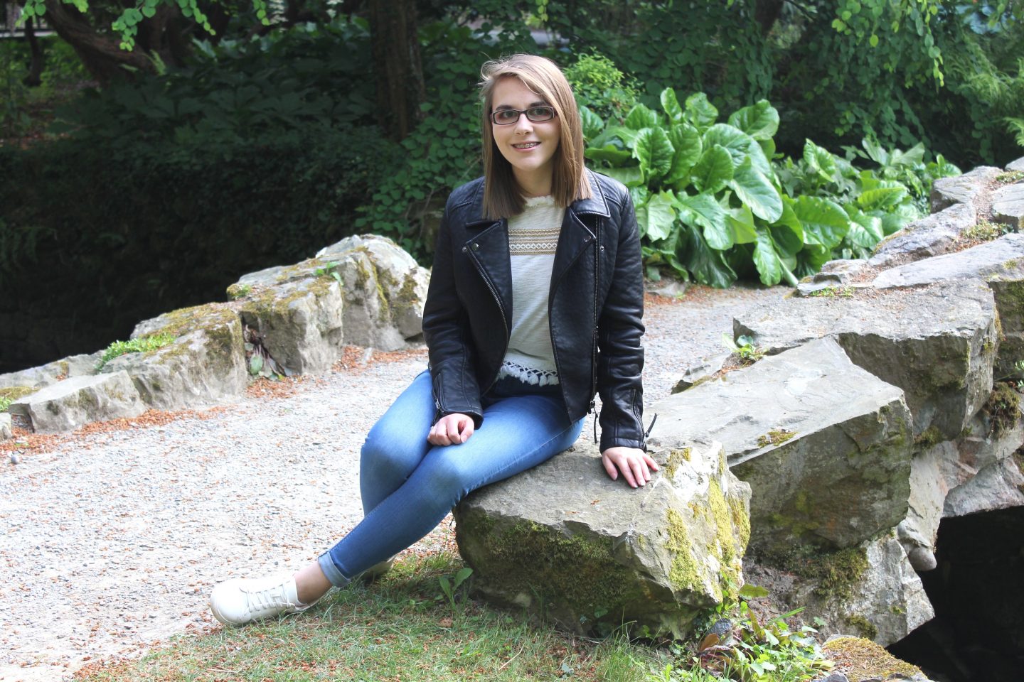 A photo of Elin sitting on a rock and smiling at the camera