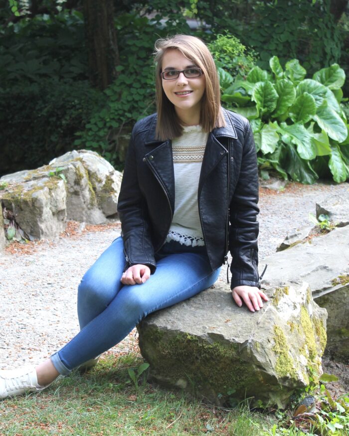 A photo of Elin sitting on a rock and smiling at the camera