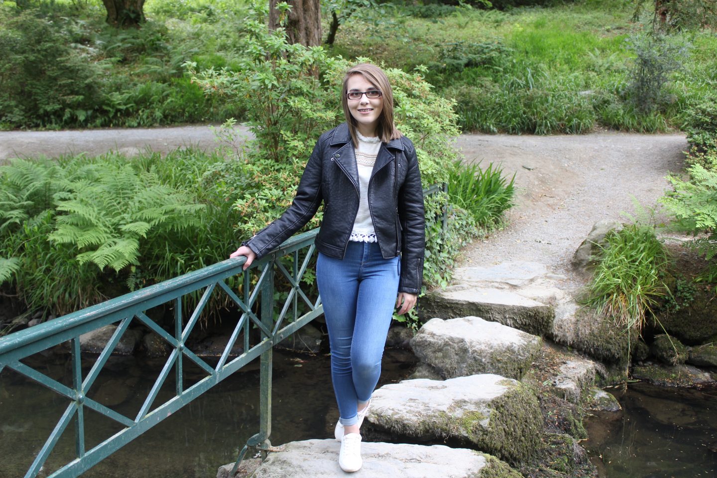 10 things I've learned about myself as a teenager: A photo of Elin wearing blue denim jeans, a white top, black leather jacket and white trainers, standing on stepping stones