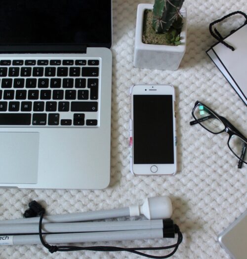 A photo of a macbook, white cane, iphone and ipad