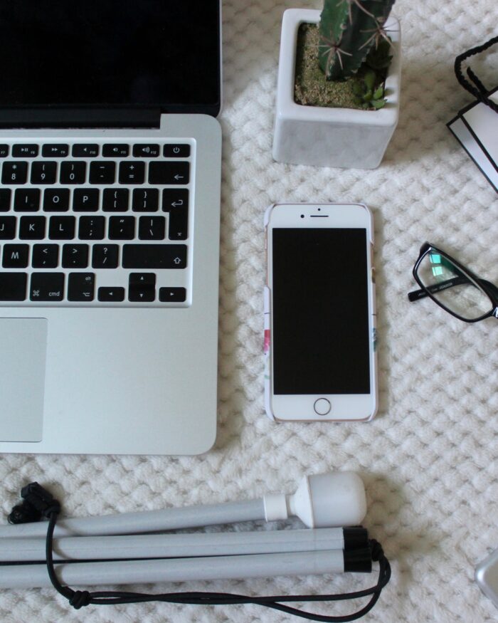 A photo of a macbook, white cane, iphone and ipad