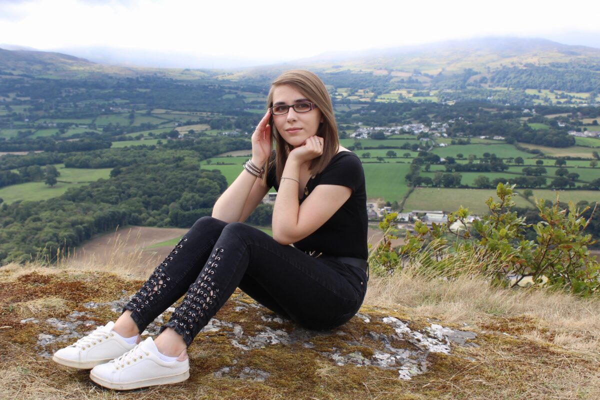 A photo of Elin wearing a black bardot top with black lace up skinny jeans