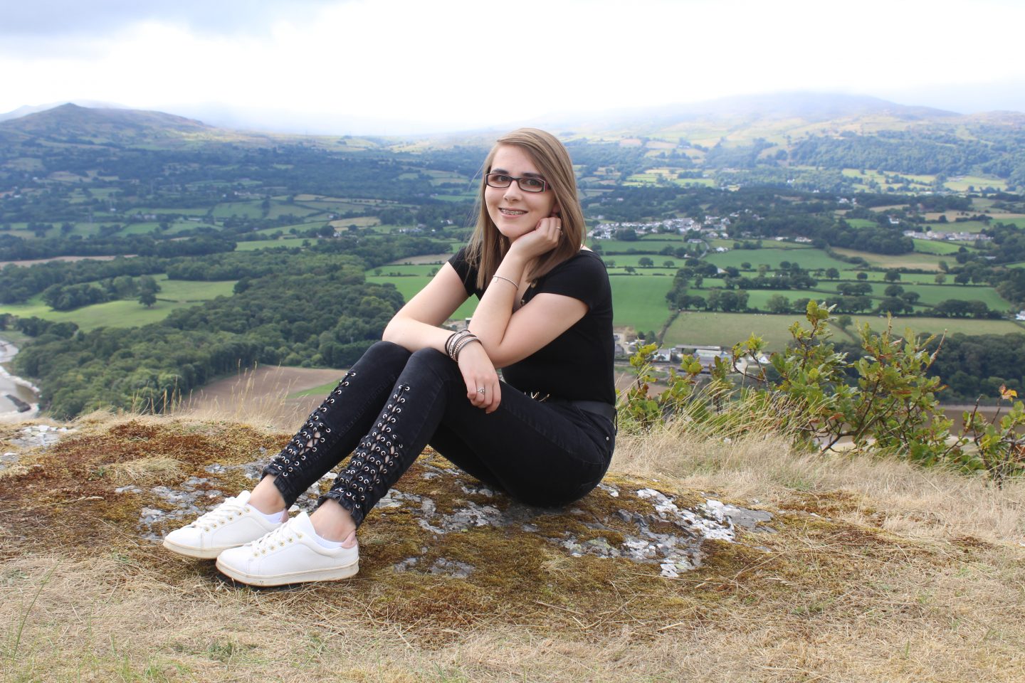 A photo of Elin wearing a black bardot top with black lace up skinny jeans
