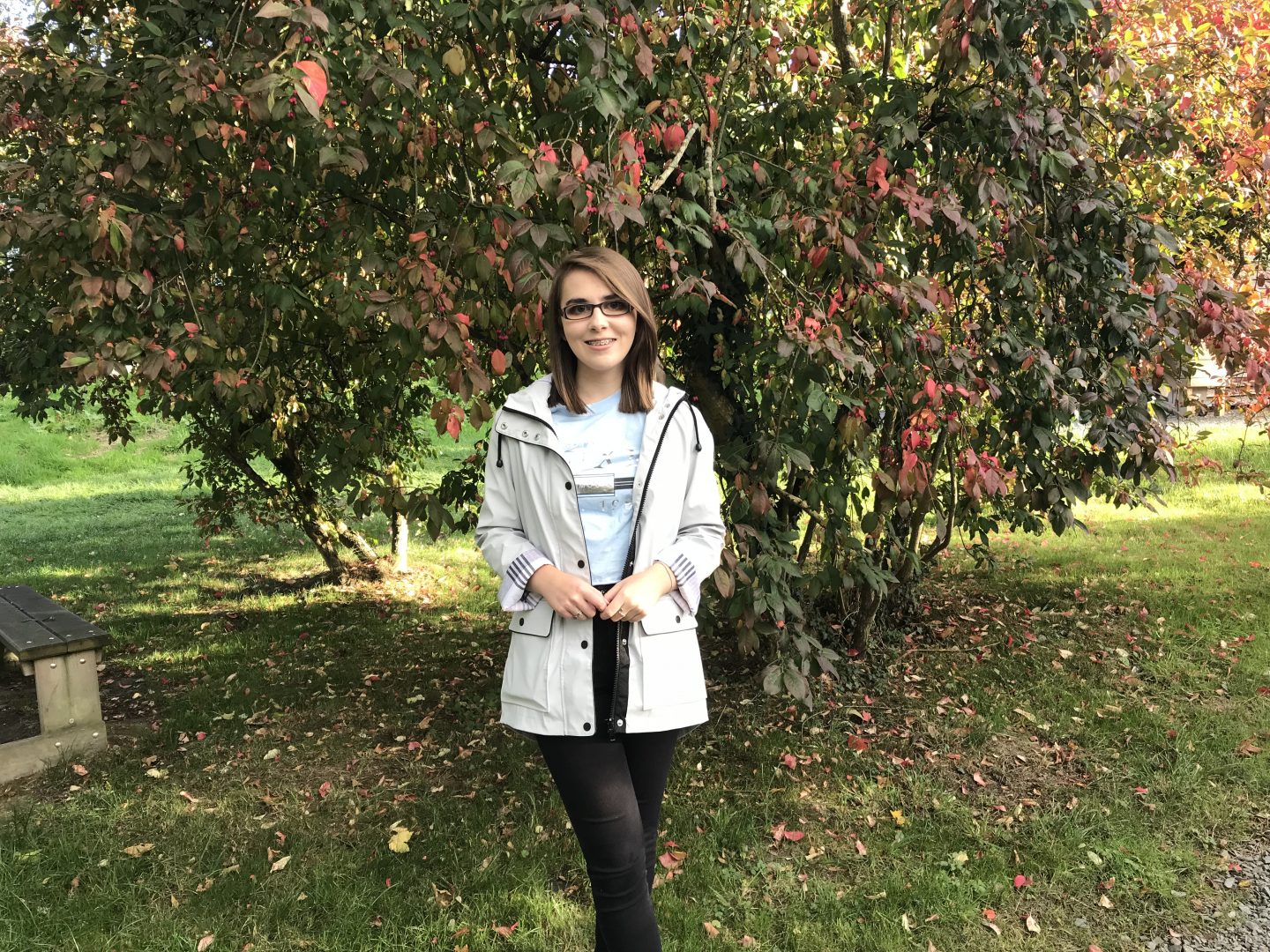 Things I wish I said when growing up with sight loss - a photo of Elin in front of a tree wich has red flowers and berries on it