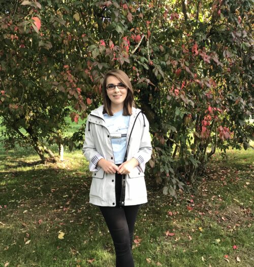 About: A photo of Elin in front of a tree wich has red flowers and berries on it