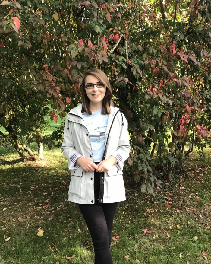 About: A photo of Elin in front of a tree wich has red flowers and berries on it
