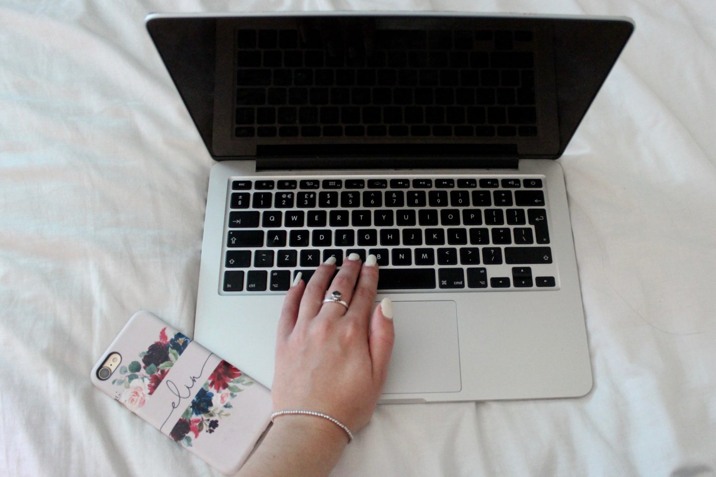 A photo of my macbook with my phone next to it which is pink and has my name on it