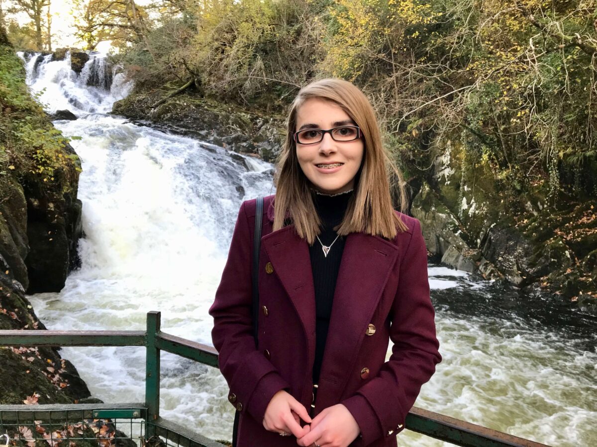 A photo of Elin standing in front of a waterfall