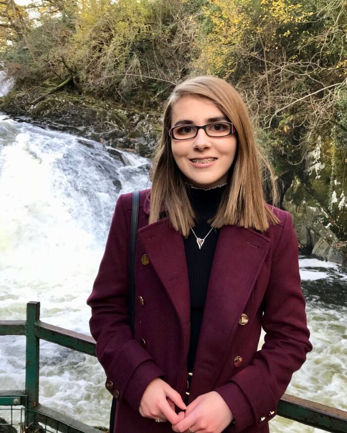 A photo of Elin standing in front of a waterfall