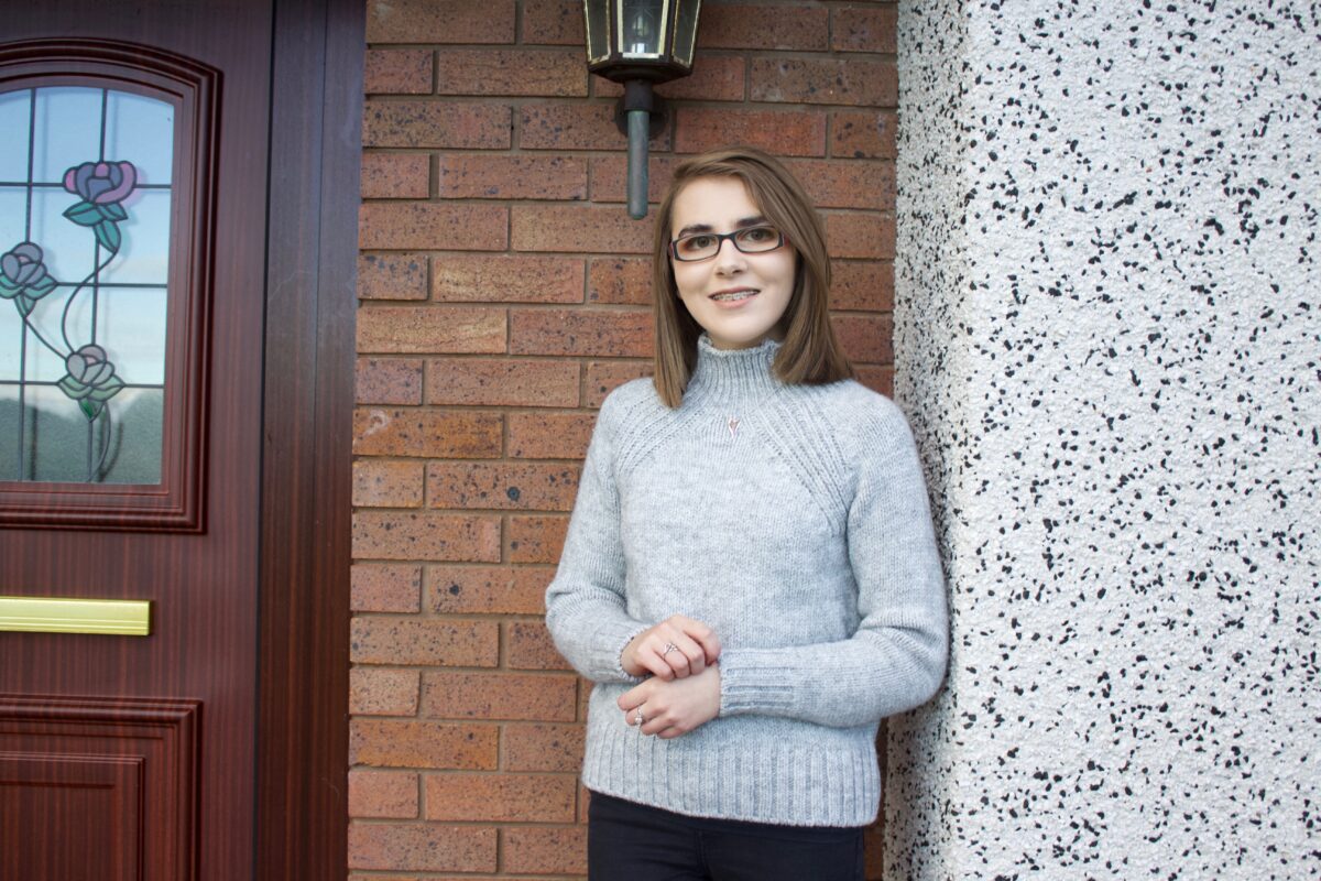A photo of Elin wearing a light grey high neck jumper