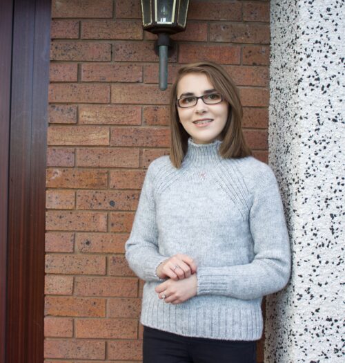 A photo of Elin wearing a light grey high neck jumper