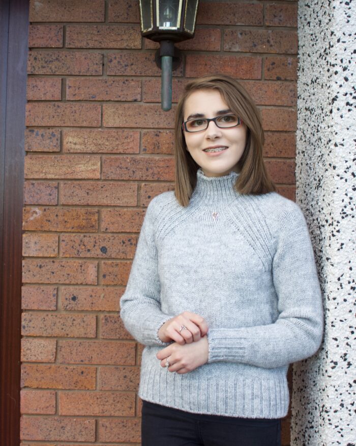 A photo of Elin wearing a light grey high neck jumper