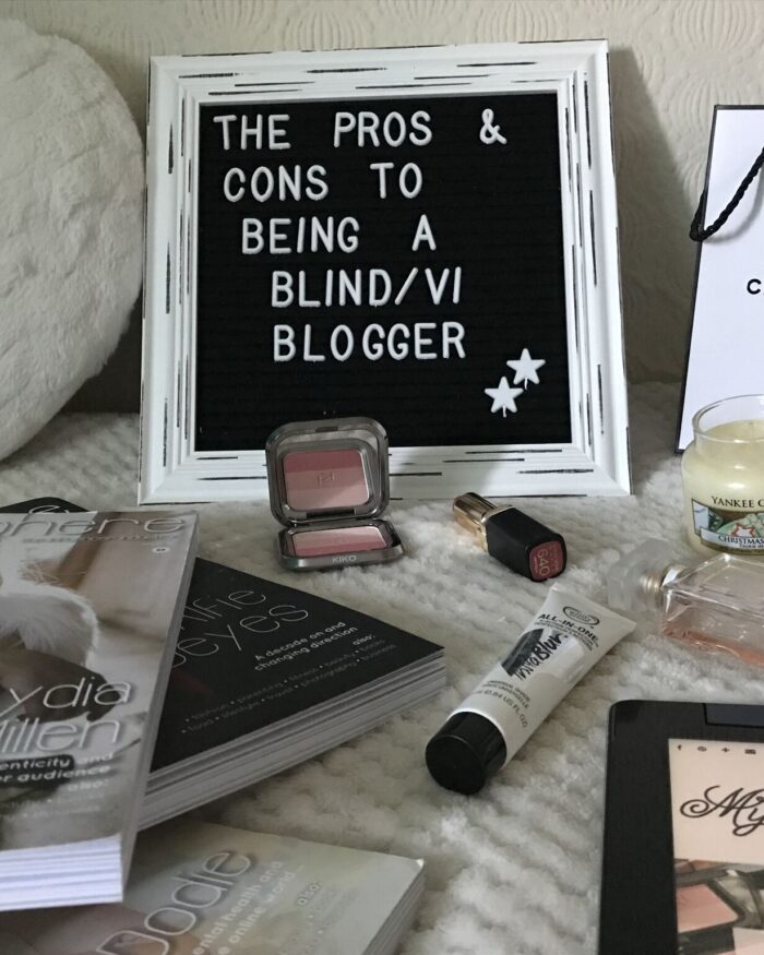 A photo of a white framed letter board which says the pros and cons to being a blind/VI blogger with beauty products in front of it and a few issues of blogosphere magazine