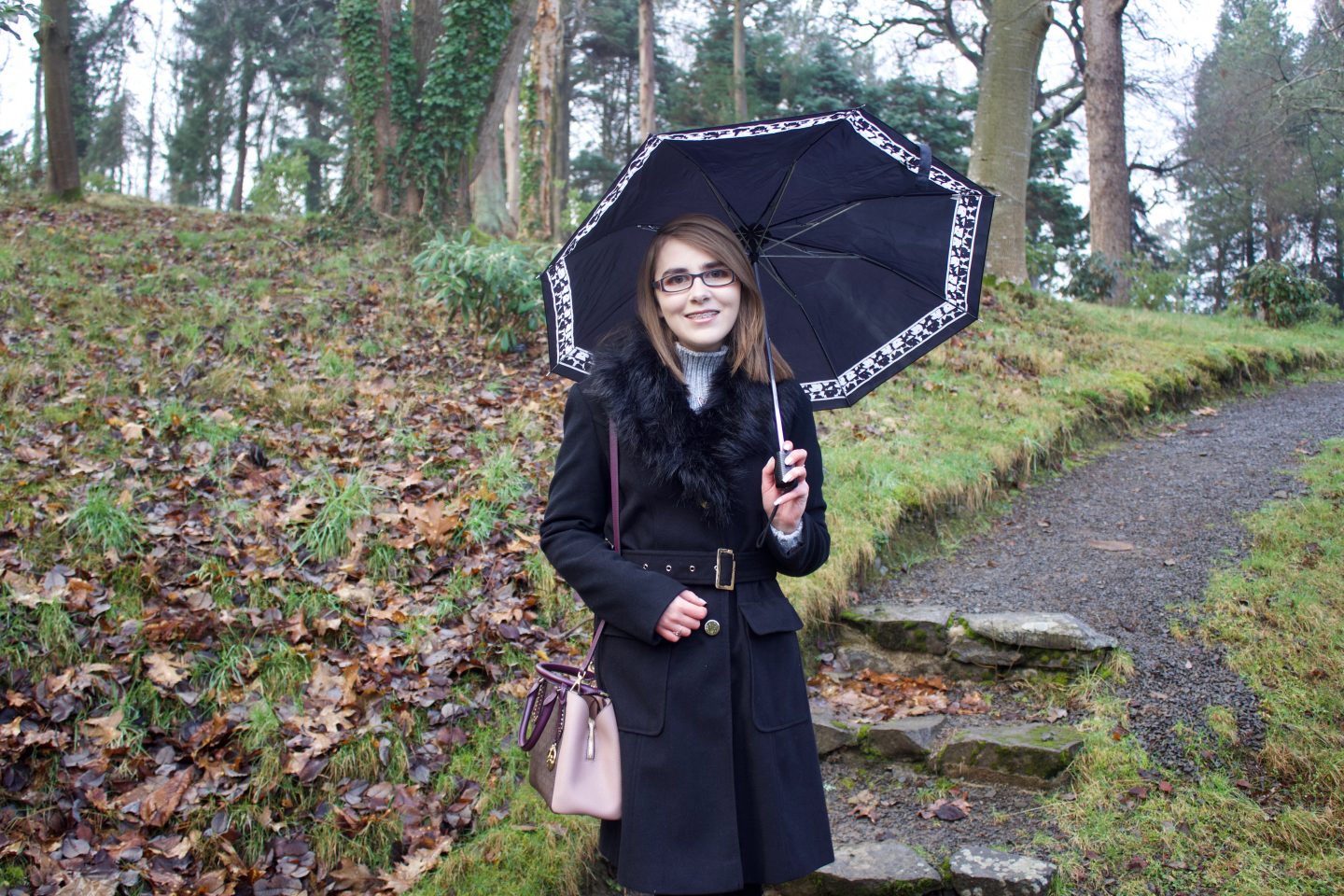 If I lived life according to the misconceptions: A photo of Elin in a black longline coat holding an umberella