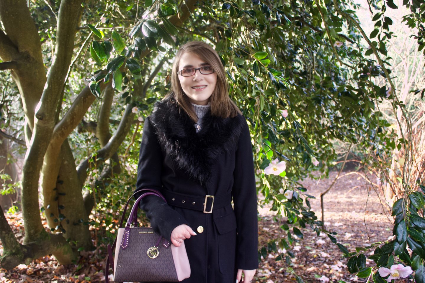A photo of Elin wearing a black count in front of trees
