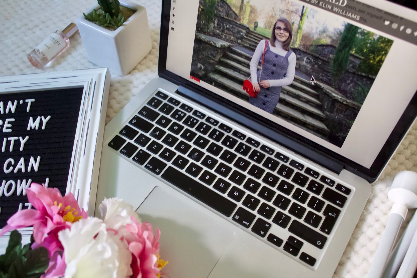 8 things that help me to love my disability: A part of one of my blog posts shows up on my macbook screen, there are some fake pink and white flowers to be seen in the bottom left hand corner of the photo, a fake cactus and a felt letter board