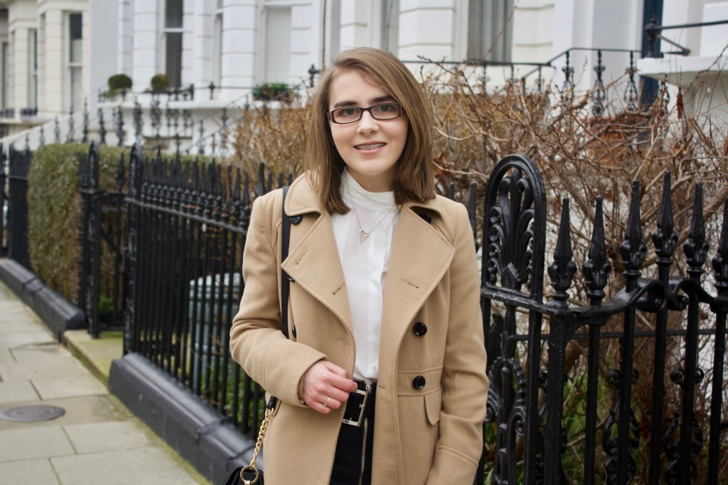 A message to young disabled people. Elin standing in front of black railings with white houses in the background