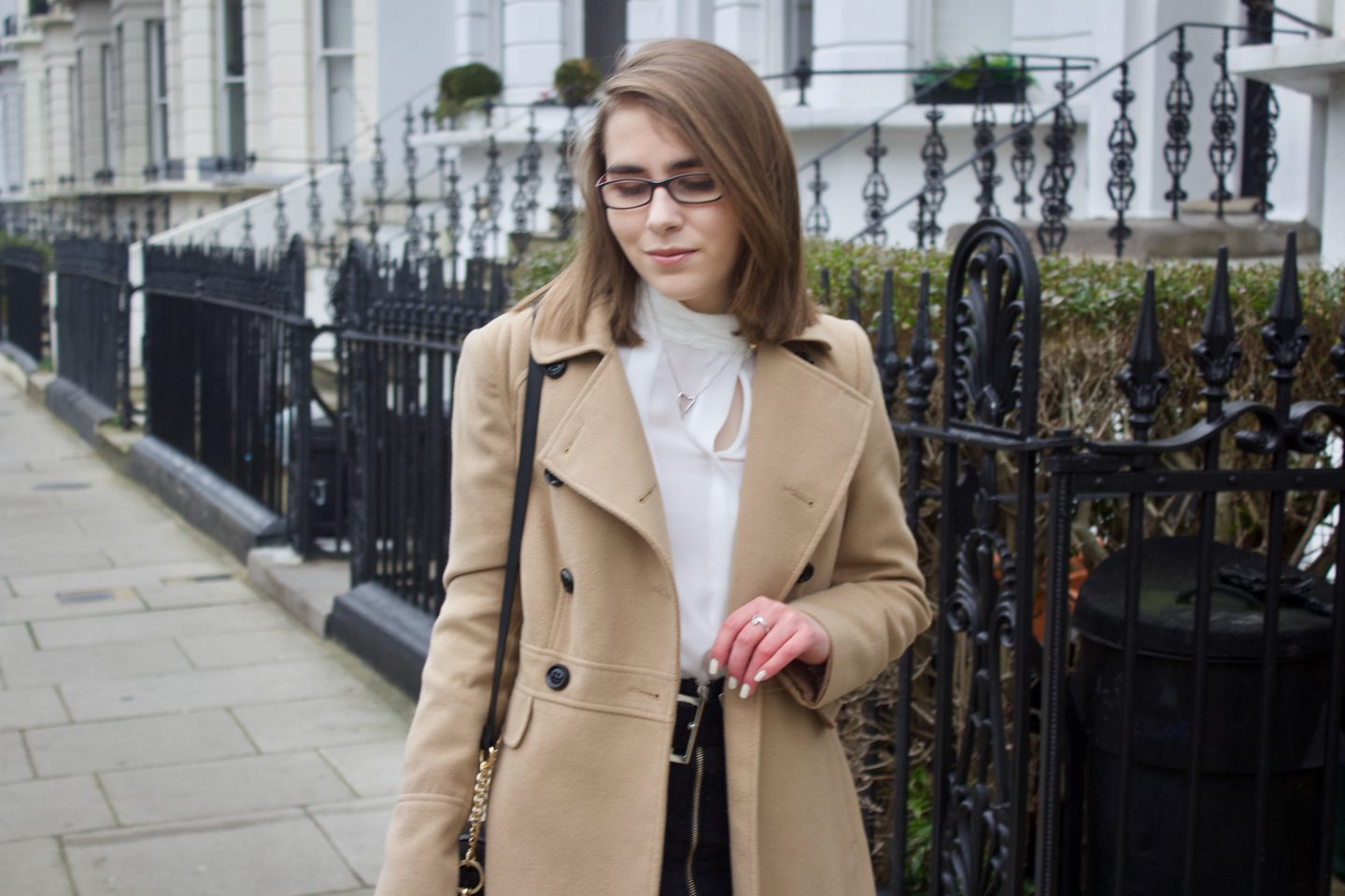 Elin looking down, there are black railings and white houses in the background