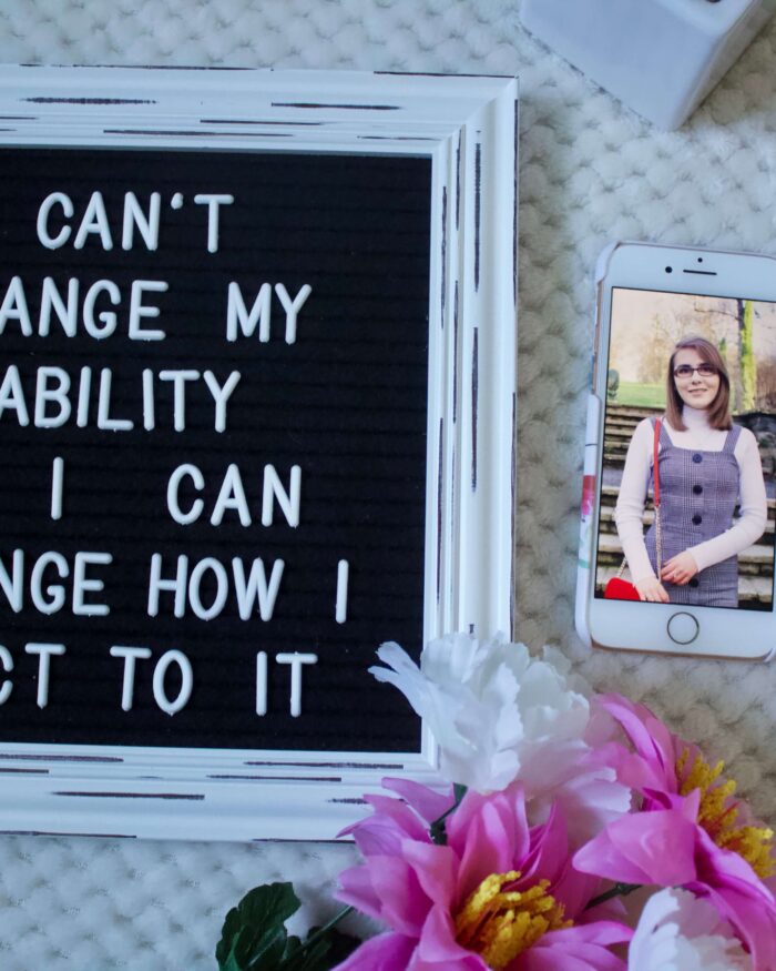 A photo of a felt letter board with the writing 'I can't change my disability but I can change how I react to it', my phone is beside it with a photo of me showing and my white cane is beside that.