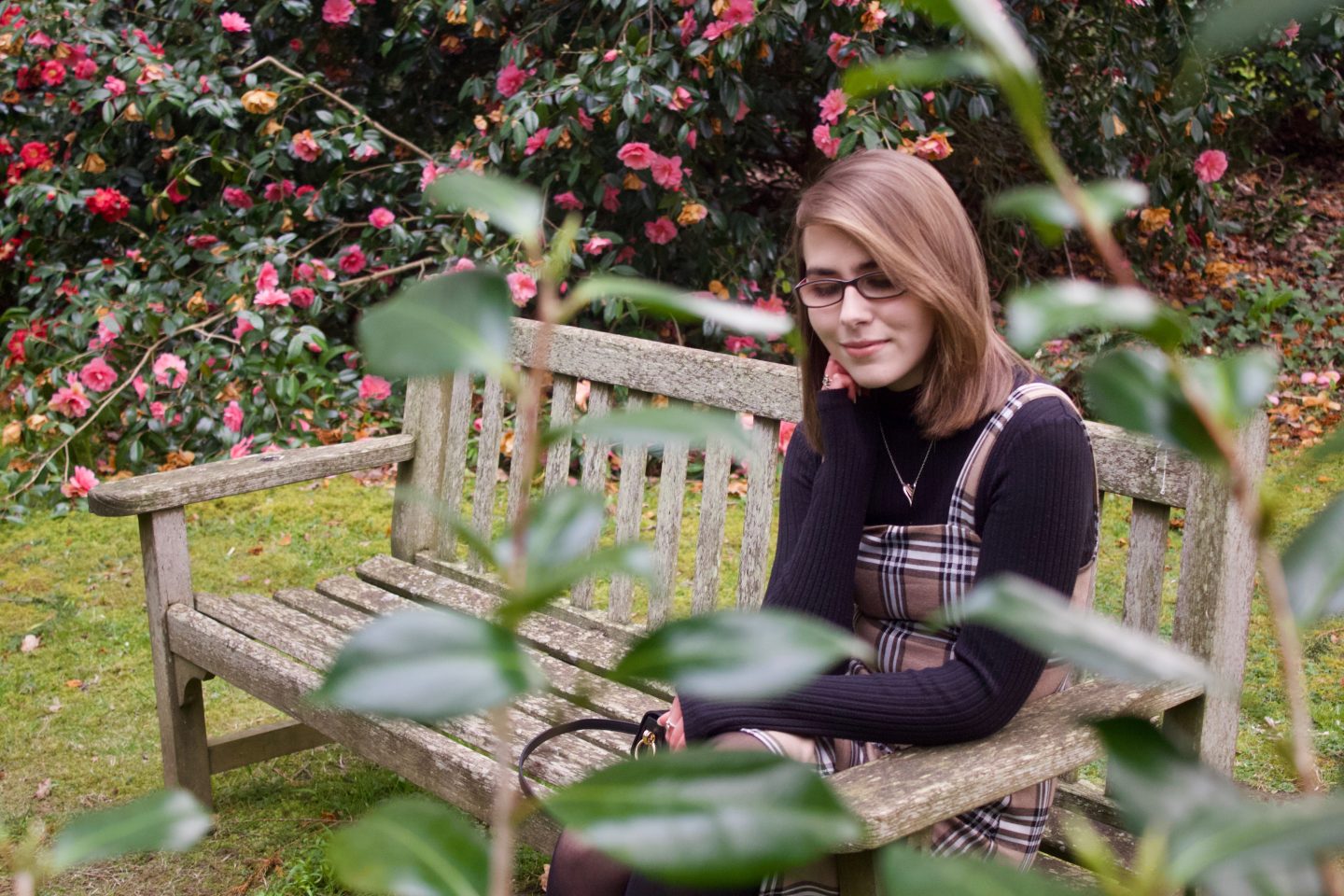A photo of Elin sitting on a bench, she is looking down