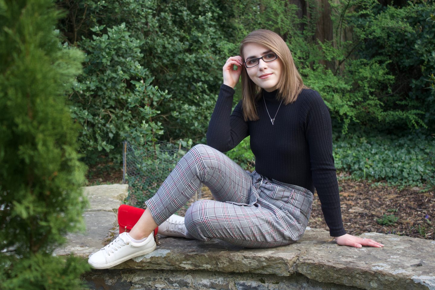 A photo of Elin wearing checked trousers, a black high neck top and white trainers
