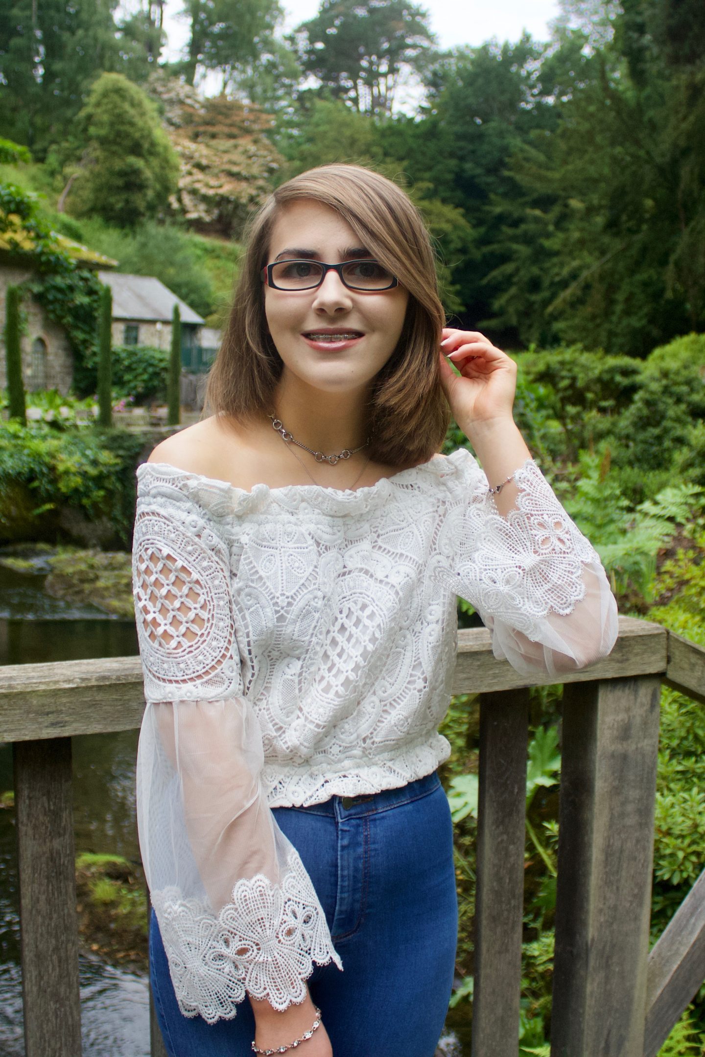 From 20 to 21: A year of personal development - A photo of Elin standing on a wooden bridge, her hand is raised and holds a strand of her hair