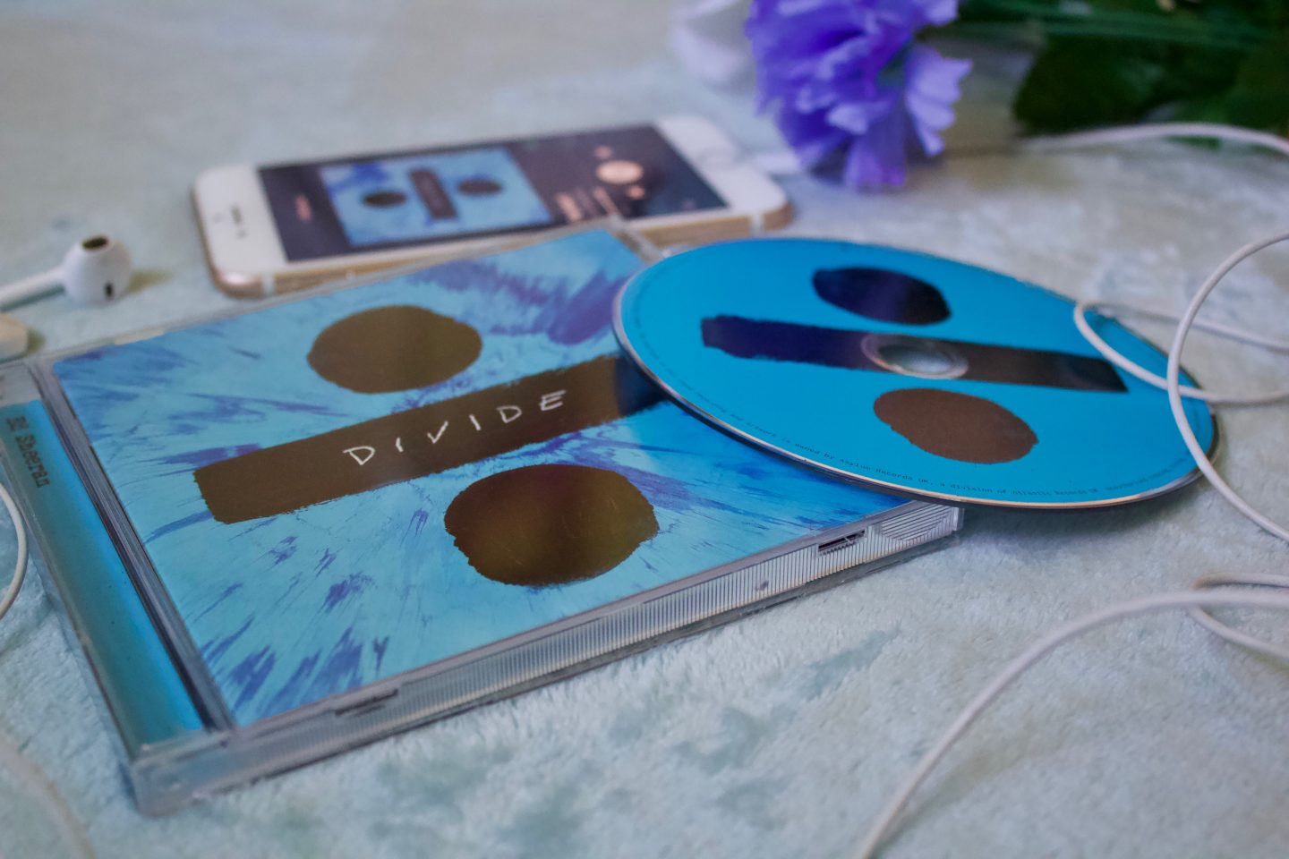 A photo of the Divide album case and CD on a light blue coloured throw