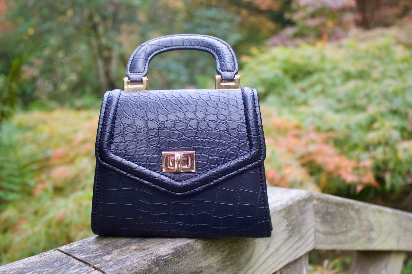 Let's talk about self-confidence: A photo of a small black bag which has croc detailing on it, there's a tiny handle on the top.