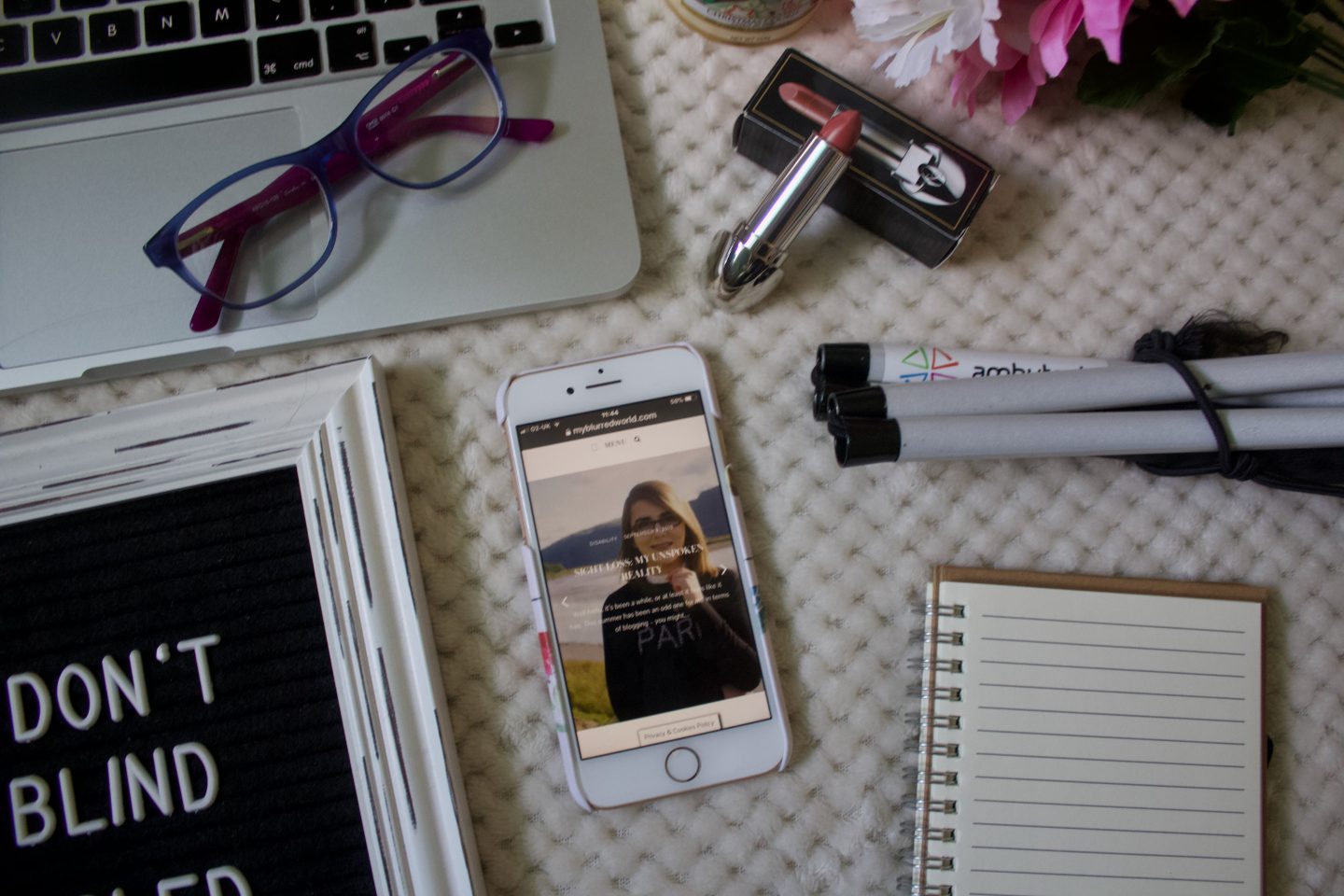 A photo of one of my blog posts on my phone, there are glasses on my laptop keyboard and a white cane in the corner of the image