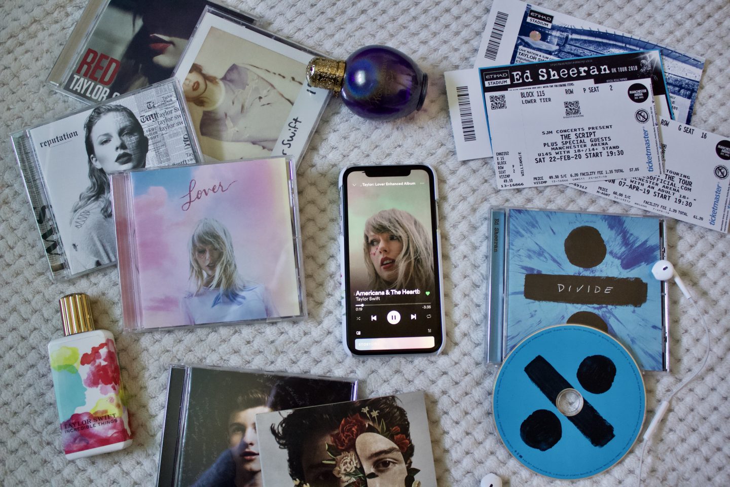A photo of Miss Americana and the heartbreak prince by Taylor Swift playing on an iPhone, there are a few albums and concert tickets surrounding it