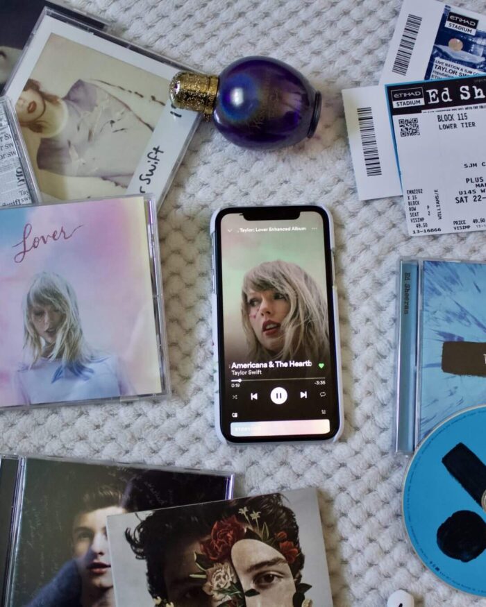 A photo of a Taylor Swift song playing on an iPhone, its surrounded by Taylor's albums including Lover, Reputation and 1989