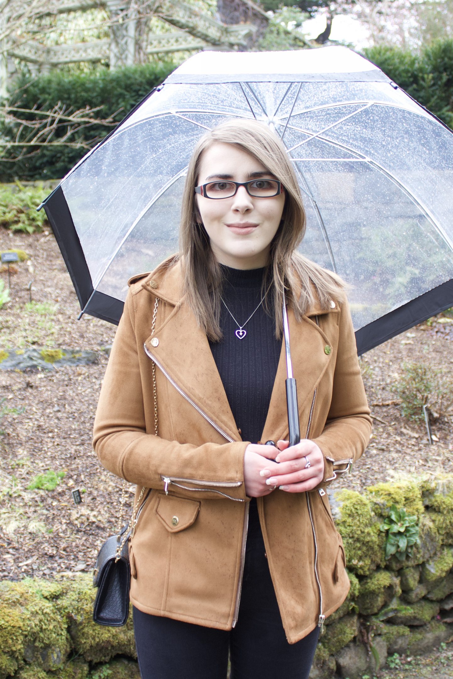 A photo of Elin wearing a black high neck top and black skinny jeans with a brown faux suede jacket