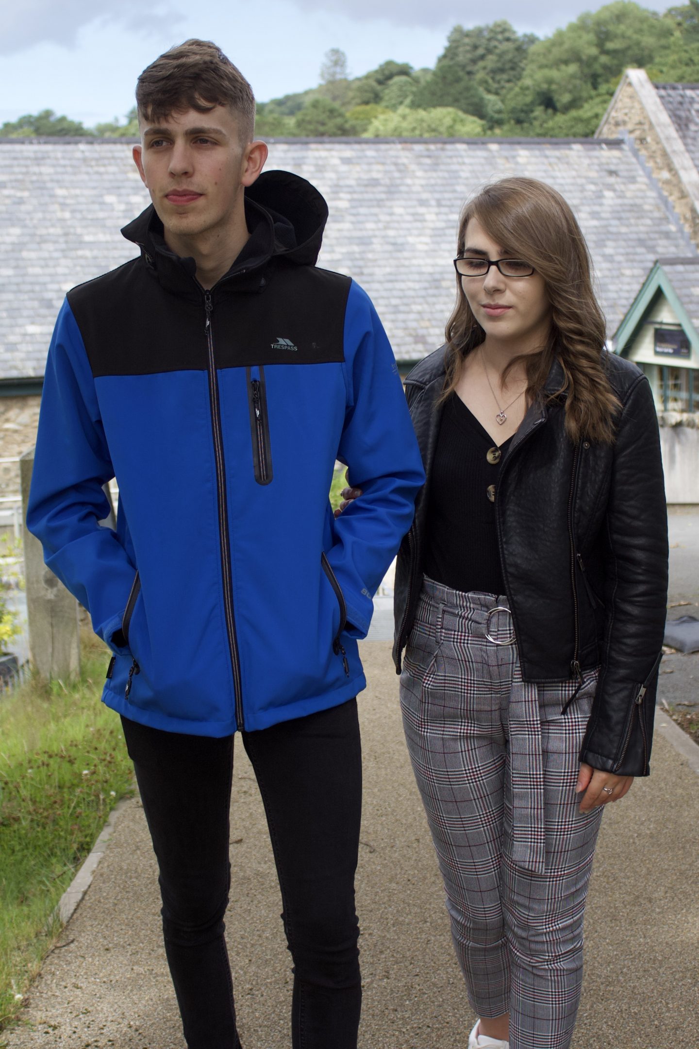 A portrait photo of my brother guiding me on a footpath with buildings behind us.