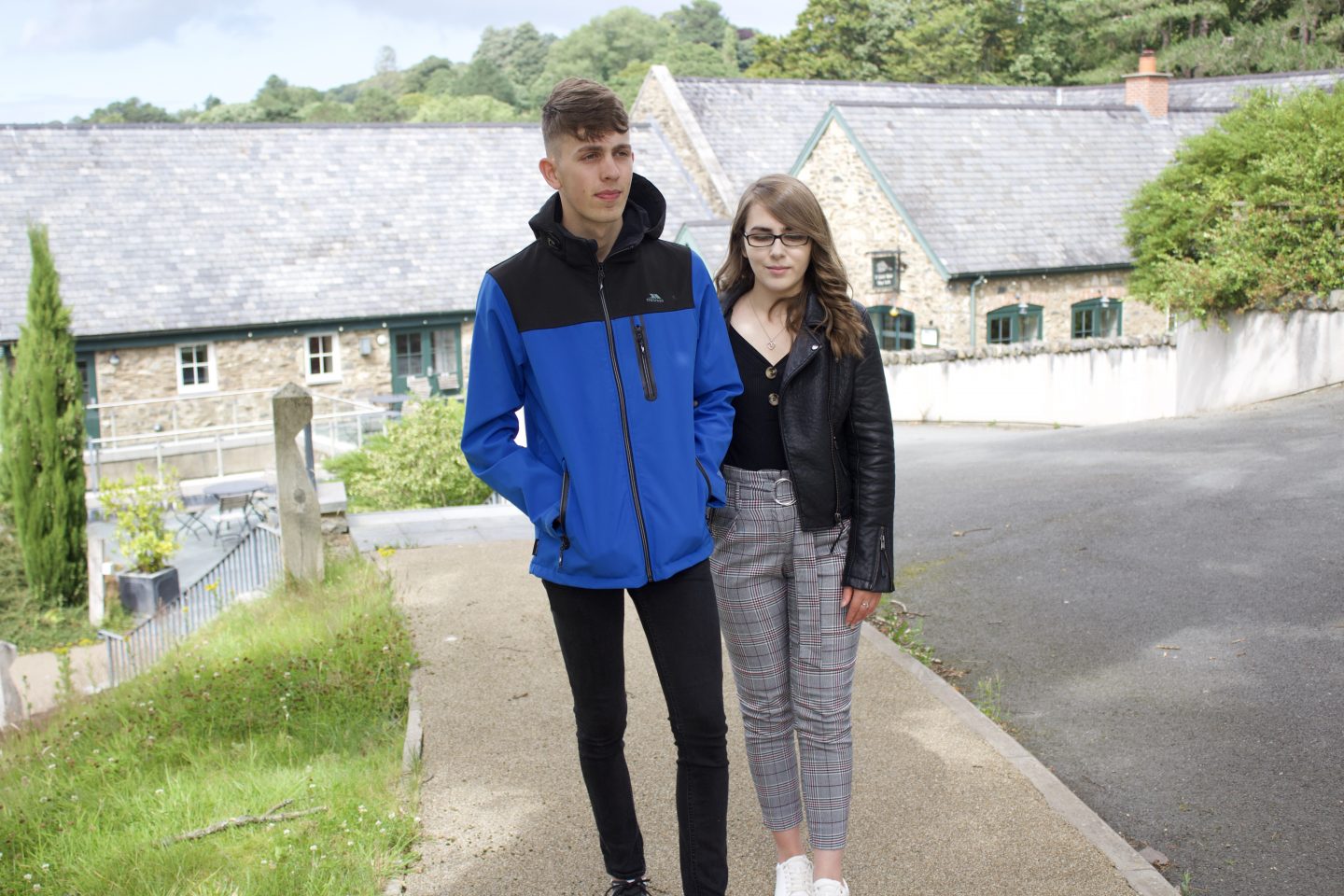 A photo of my brother and I walking on a path with pretty old fashioned buildings in the background. I'm holding my brother's elbow as he guides me