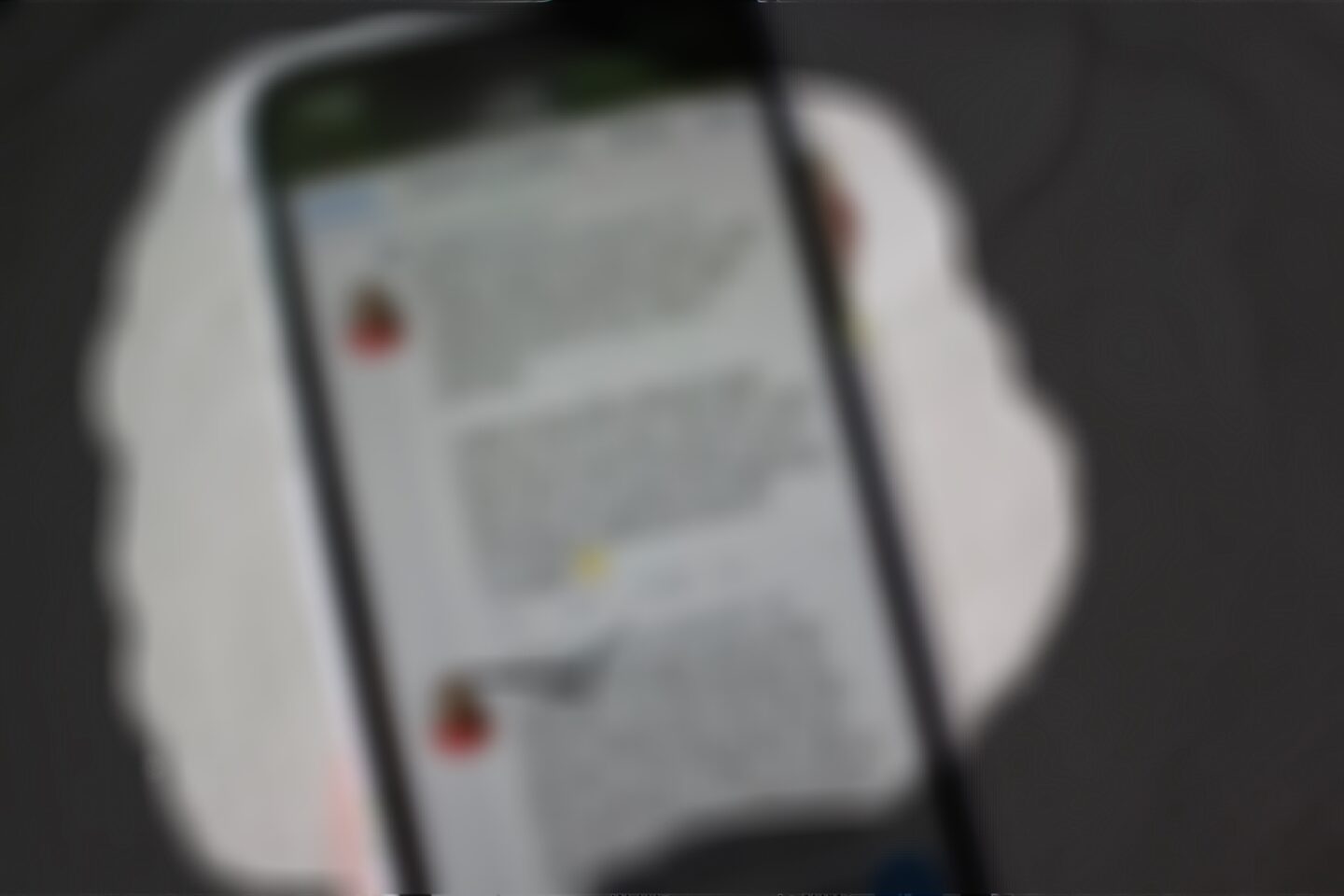 A photo of my phone screen which is blurred so none of the writing can be made out, the edges of the view are dark