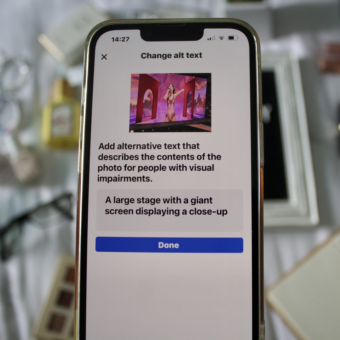 A phone displaying Facebook's 'Change ALT text' page. At the top is a photo of Taylor Swift on stage at The Eras Tour, below is text that says Add alternative text that describes the contents of the photo for people with visual impairments. Below this is a snippet of the photo's description which says A large stage with a giant screen displaying a close-up... At the bottom is a blue button with white text saying 'Done'